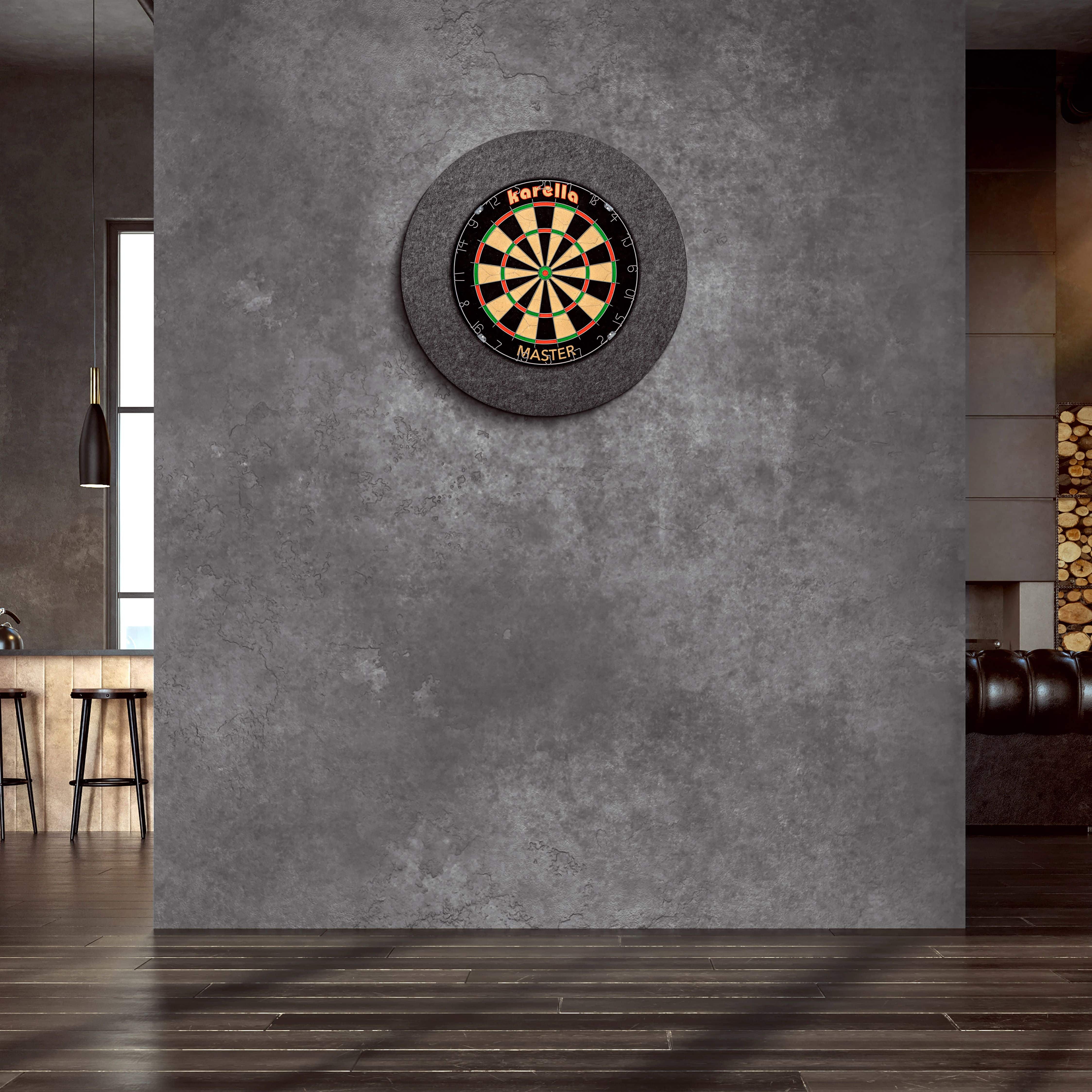 Cornice per bersaglio in acciaio Karella Ultimo An der Wand hängt ein "Karella Ultimo Steeldartboard Surround". Der Raum wirkt modern und stilvoll mit dunklen Farben und eleganter Einrichtung.