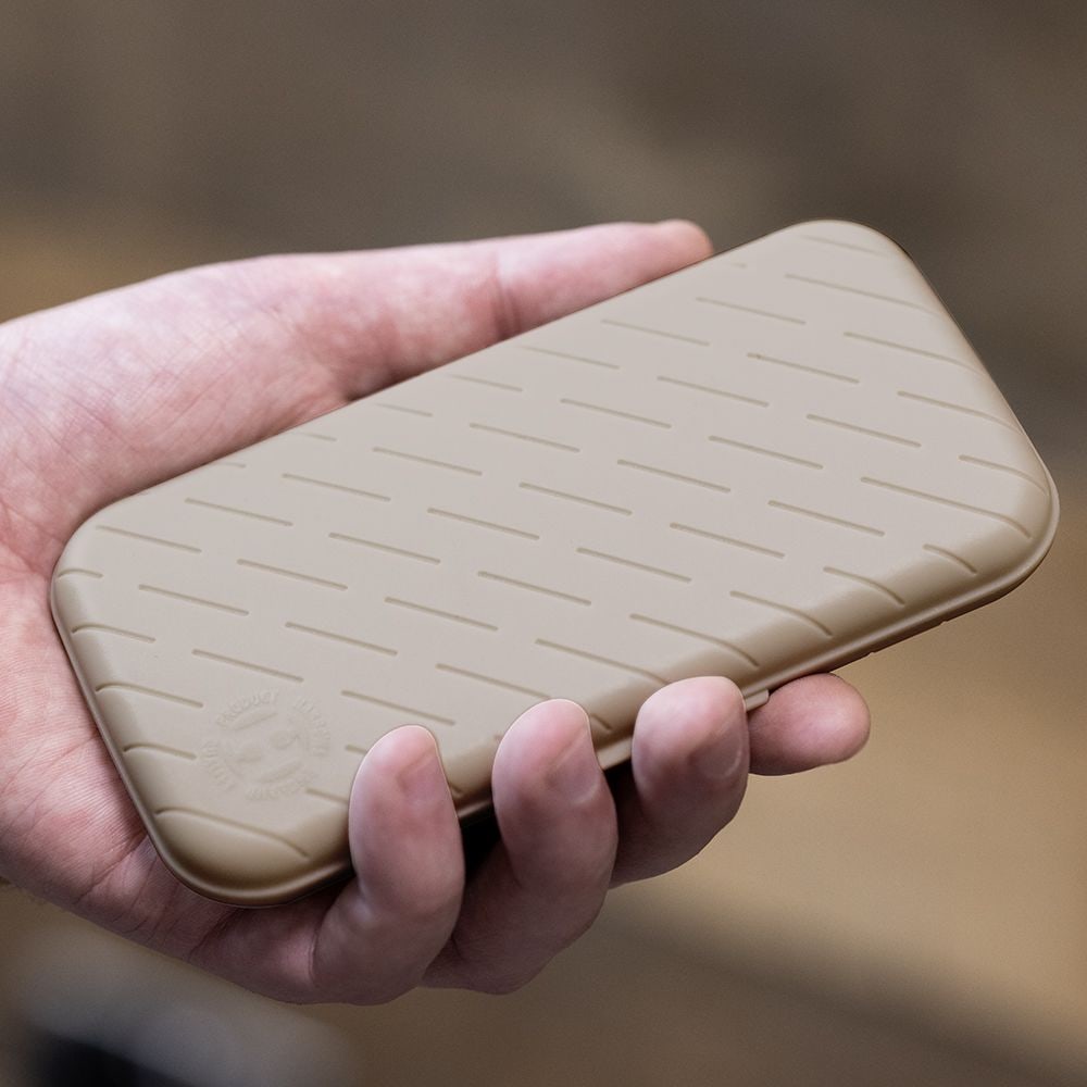 Custodia per freccette Harrows Slimcase Eine Hand hält ein schlankes, steingraues Etui mit einem dezenten Muster. Das Etui wirkt stabil und ist wahrscheinlich für Dartzubehör gedacht.