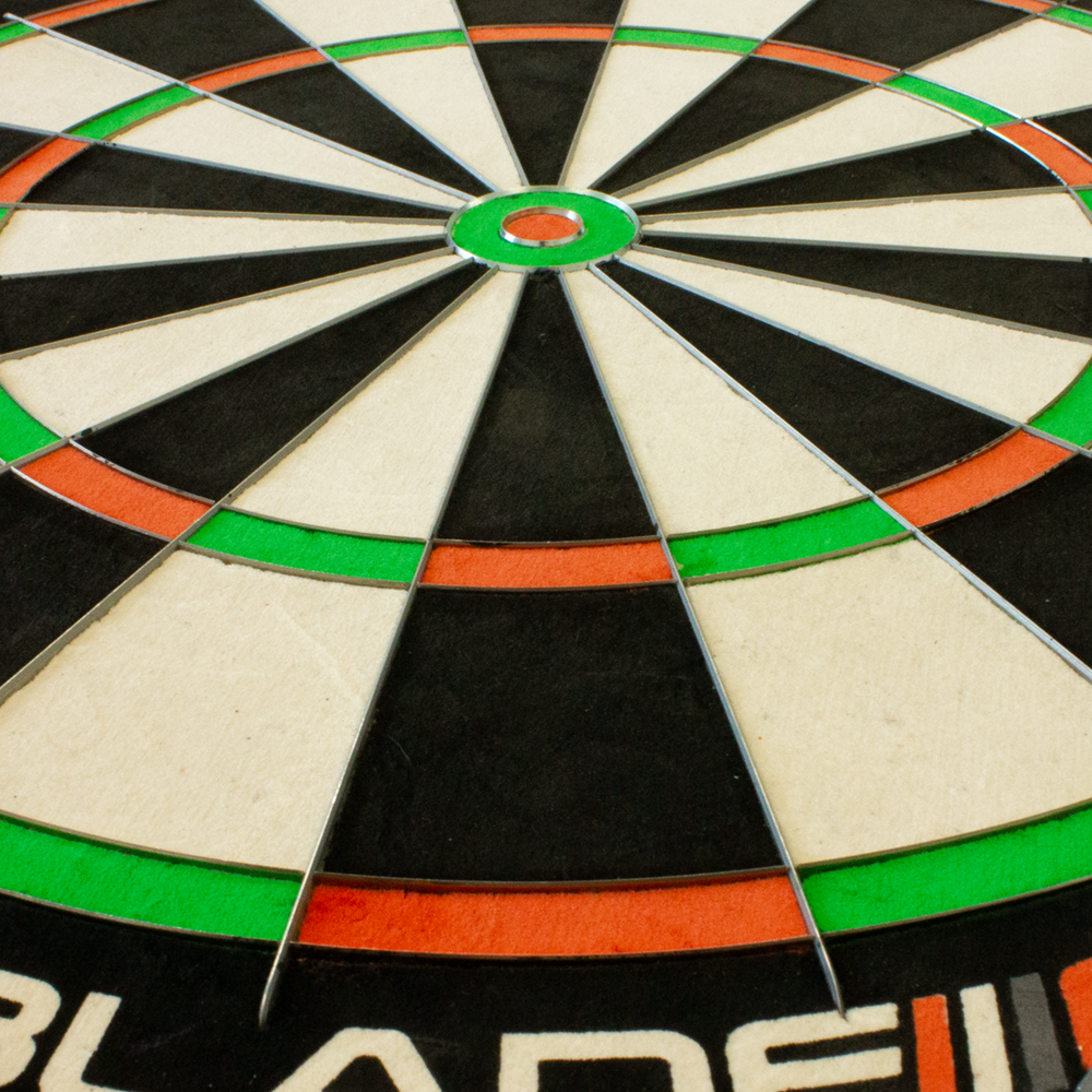 3032_Winmau_Blade_6_TripleCore_Steeldartboard_4 Das Bild zeigt eine Nahaufnahme des Winmau Blade 6 TripleCore Steeldartboards. Deutlich zu sehen sind die farbigen Segmente sowie das Bullseye in der Mitte.