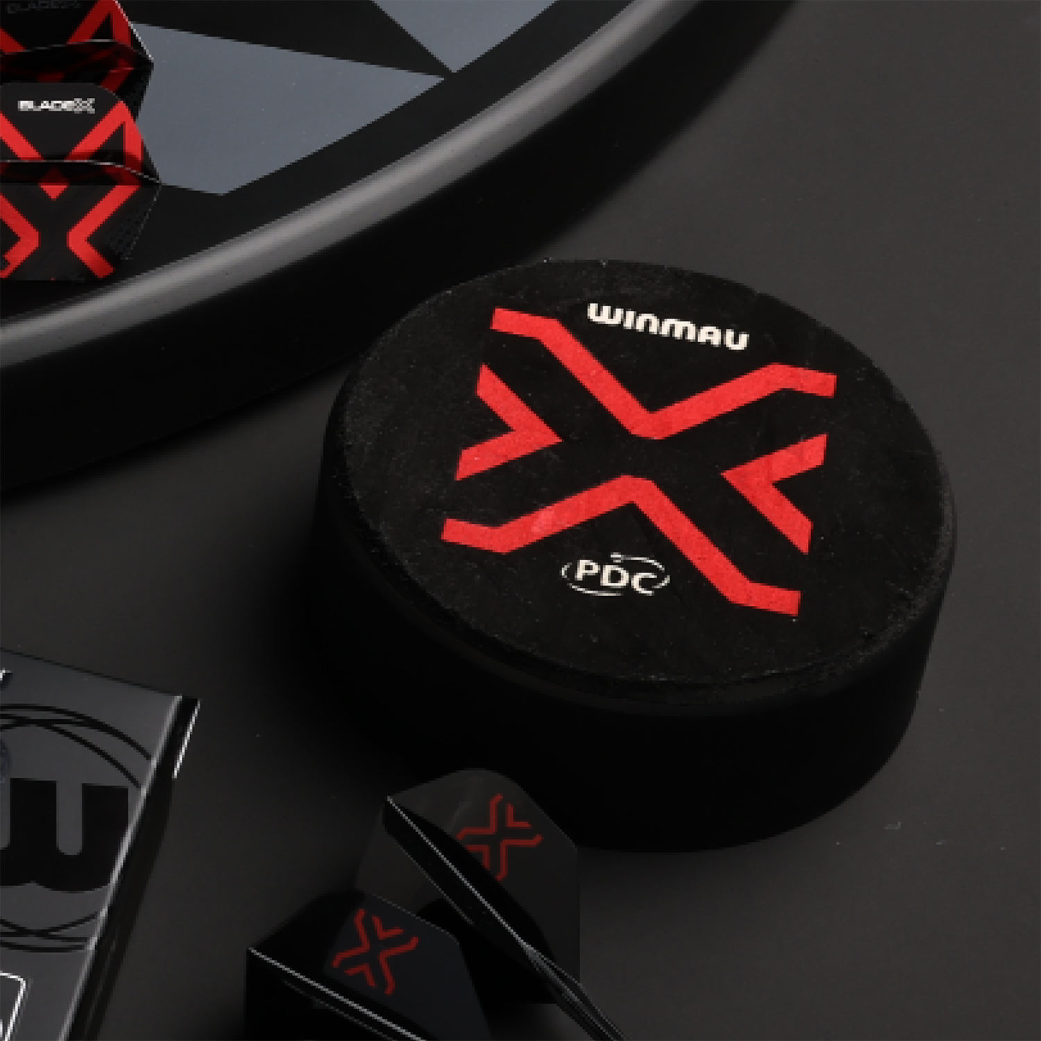 Supporto per freccette Winmau Dart Dock Blade X Der Winmau Dart Dock Blade X Dartständer ist auf dem Bild zu sehen. Es handelt sich um einen modernen Dartständer für Dartspieler.