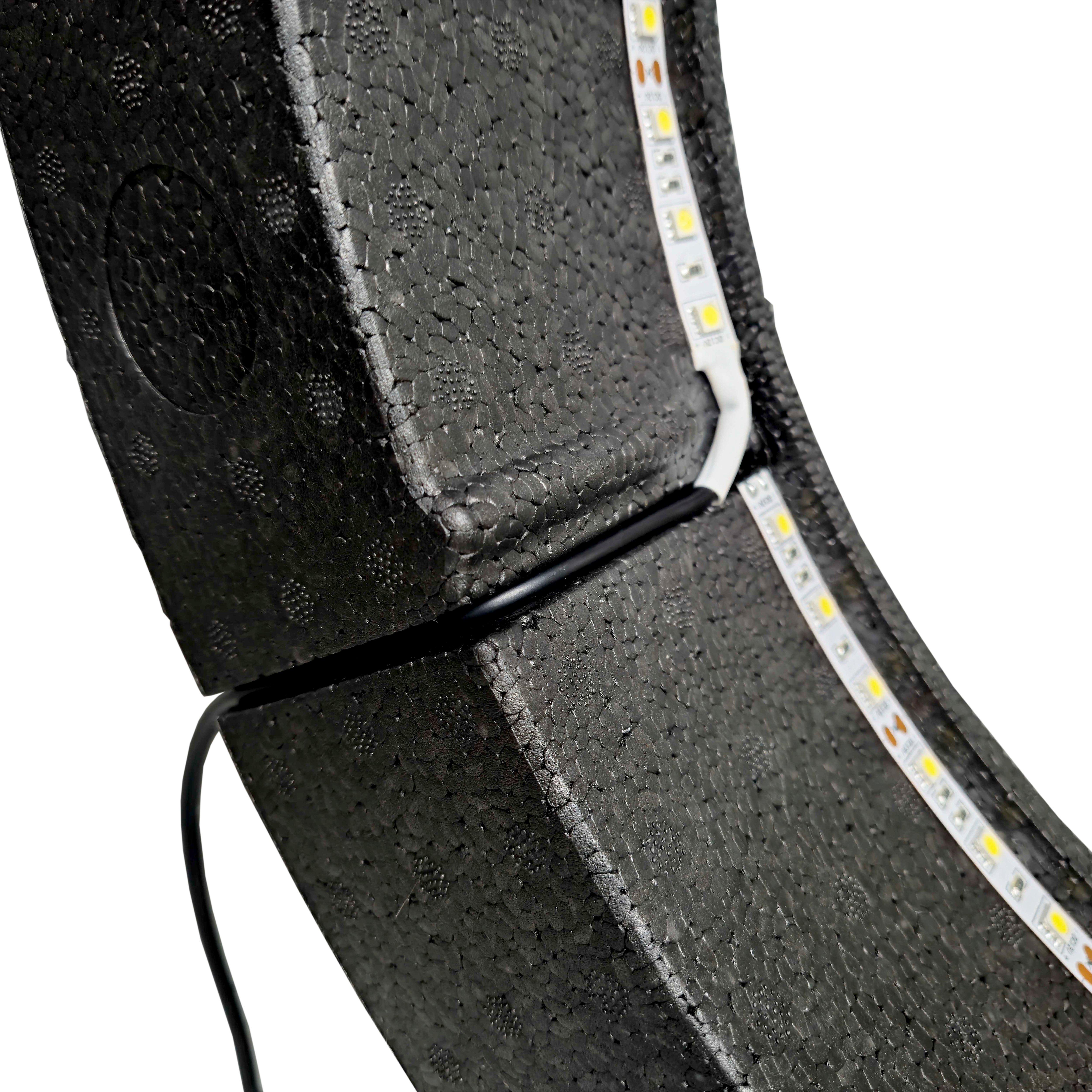 Sistema di illuminazione Bulls NL Lumo Light Surround Das Bild zeigt das „Bulls NL Lumo Light Surround Beleuchtungssystem“ mit LED-Leuchtstreifen auf einer schwarzen, strukturierten Oberfläche. Ein Kabel ist ebenfalls an das Beleuchtungssystem angeschlossen.