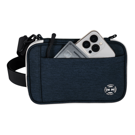 Portafoglio per freccette Harrows Smart Case XL Eine blaue Tasche mit Vorderfach enthält ein Smartphone und eine Kreditkarte. Am unteren Rand der Tasche befindet sich ein rundes weißes Logo.