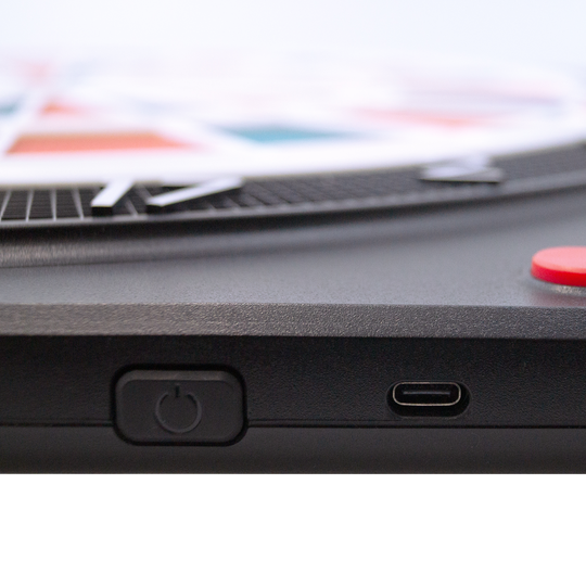 Bersaglio elettronico morbido Karella CB-Smart Das Bild zeigt einen Ausschnitt der Karella CB-Smart Elektronische Soft-Dartscheibe. Zu sehen sind der Ein-/Ausschalter und ein USB-C Anschluss an der Seite des Geräts.