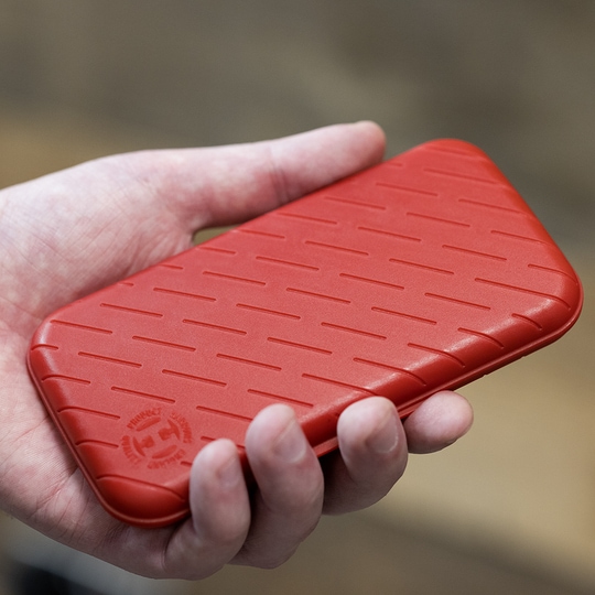 Custodia per freccette Harrows Slimcase Eine Person hält eine rote, strukturierte Darttasche in der Hand. Die Darttasche hat eine schlanke und kompakte Form.