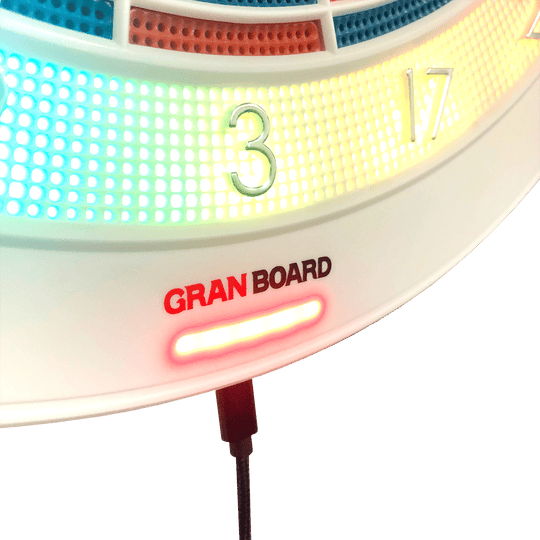 g01440_GranBoard_132_Elektronisches_Dartboard_4 Das Bild zeigt einen Ausschnitt des elektronischen Dartboards "GranBoard 132" mit leuchtenden LED-Lichtern um die Zahlenbereiche. Darunter ist das Logo "Gran Board" in roten und schwarzen Buchstaben zu sehen.