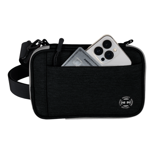 Portafoglio per freccette Harrows Smart Case XL Auf dem Bild ist eine schwarze Harrows Smart Case XL Darttasche zu sehen. In der vorderen Tasche stecken ein Smartphone und eine Kreditkarte.