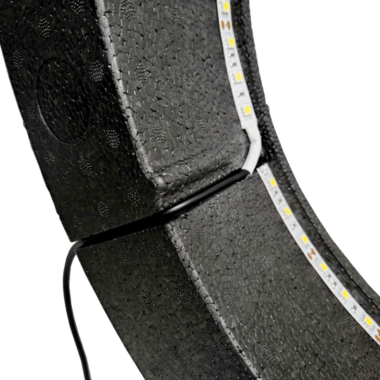 Sistema di illuminazione Bulls NL Lumo Light Surround Das Bild zeigt das „Bulls NL Lumo Light Surround Beleuchtungssystem“ mit LED-Leuchtstreifen auf einer schwarzen, strukturierten Oberfläche. Ein Kabel ist ebenfalls an das Beleuchtungssystem angeschlossen.